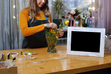 florist girl in an apron to work on creating a creative bouquet for a client. online order preparation concept