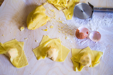 hand of the Italian housewife preparing egg pasta, ravioli and tortelli, stuffed with pumpkin filling and sausage,, for the party lunch.