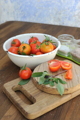Ripe organic tomatoes in bowl on board
