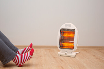 female feet standing on parquet floor, in front of halogen heater, Front view, 