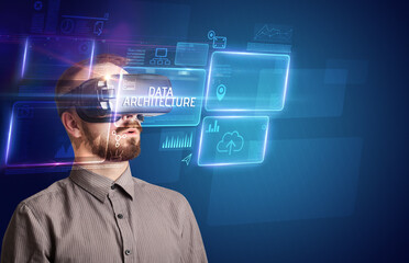 Businessman looking through Virtual Reality glasses with DATA ARCHITECTURE inscription, new technology concept