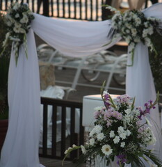 bramka wejściowa ozdobiona wiązankami kwiatów i zwiewną białą woalą przed ślubem