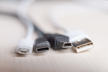 Mini USB, micro USB, and USB type-C connectors, with connecting cables, photographed closely. Evolution and change of USB connectors.