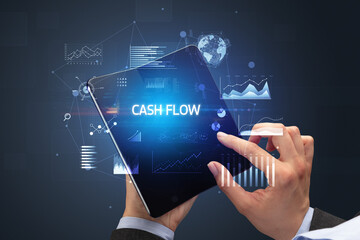 Businessman holding a foldable smartphone with CASH FLOW inscription, successful business concept