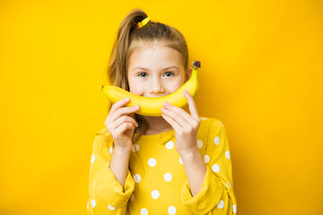 Happy little child girl with yellow banana like smile on yellow background