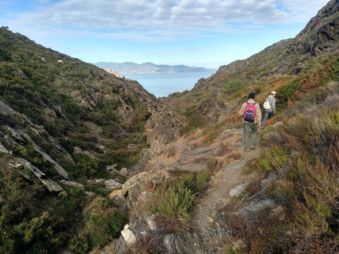 Senderistas caminando por la monta&ntilde;a para llegar a la caleta de Prona, en Port de la Selva (Girona)