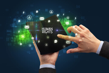 Businessman holding a foldable smartphone with HUMAN RIGHTS inscription, social networking concept
