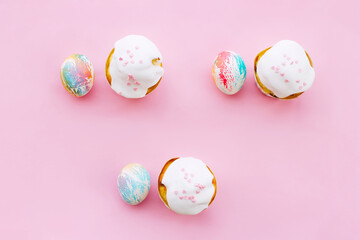 easter colored eggs and cupcakes covered with icing on a pink background