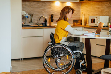 Female in wheelchair using laptop at home