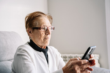 Elderly woman using smartphone at home