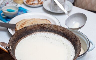 The process of frying pancakes in a frying pan. Preparation for the celebration of Maslenitsa. Selective focus.