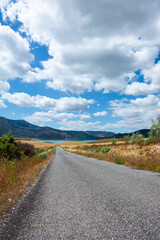 Road to the lake in the mountains with blue sky and clouds