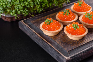 Delicious fresh red caviar on a dark concrete table