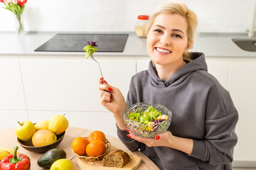 Obraz premium Beautiful young woman is preparing vegetable salad in the kitchen. Cooking At Home