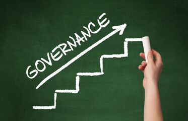 Hand drawing GOVERNANCE inscription with white chalk on blackboard, business concept