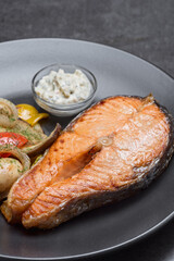 Salmon steak with champignon and vegetables on the grill at the black plate