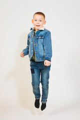 Blond boy in denim jacket jumps up. Child is happy. Feeling of excitement and joy in children 