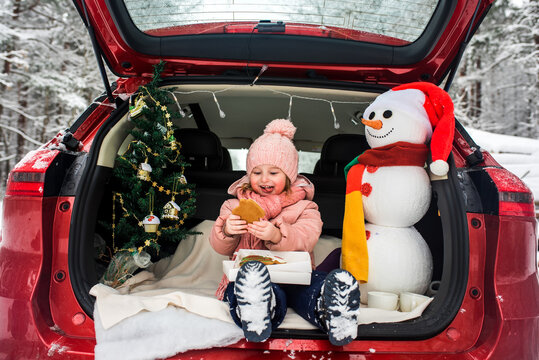 children in the trunk of a car in winter, christmas tree and snowman, merry holidays, hot tea and gingerbread, picnic in the forest