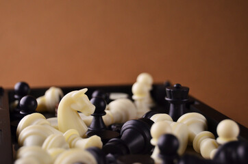 Chess figures of white and black color close-up on a brown background with copy space. High quality photo