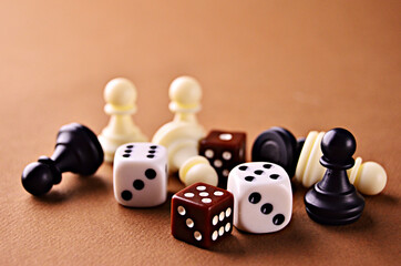 White and brown dice with white and black walking sticks with a close-up on a brown background....