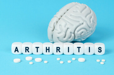 Cubes lie on the table among the pills and imitation of the brain. The text on the dice - ARTHRITIS