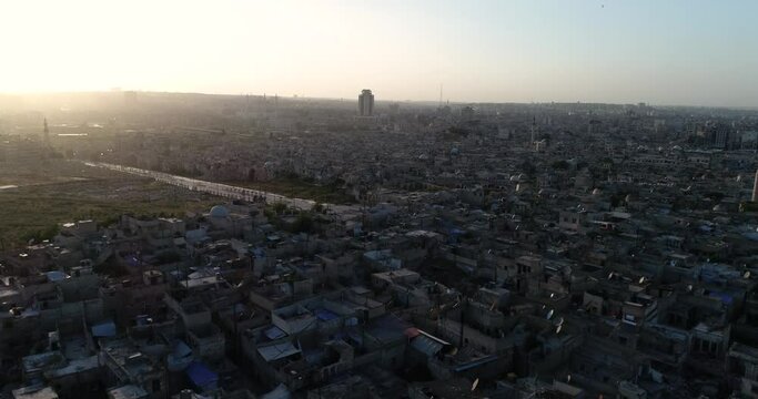 Aerial view with a drone above a syrian city under the sunrise. We can see the city of Aleppo all over the horizon 4K