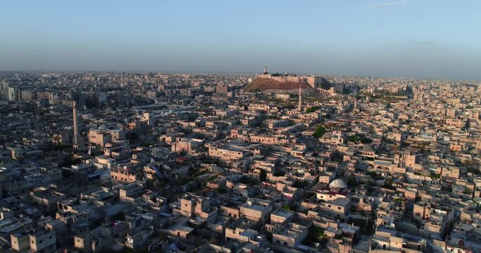 Aerial view with a drone of the citadel of Aleppo under the sunset. We can see the syrian city all over the horizon 4K