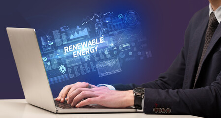 Businessman working on laptop with RENEWABLE ENERGY inscription, cyber technology concept