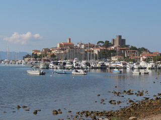 Fototapeta na wymiar Panorama of the fortified medieval village of Talamone and of its coast lapped by the Tyrrhenian Sea with the boats moored in the port