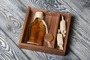Gift alcohol. A bottle of alcohol and candy are in a wooden box.