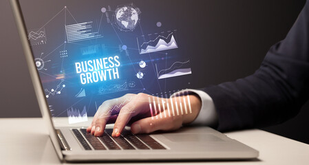Businessman working on laptop with BUSINESS GROWTH inscription, new business concept