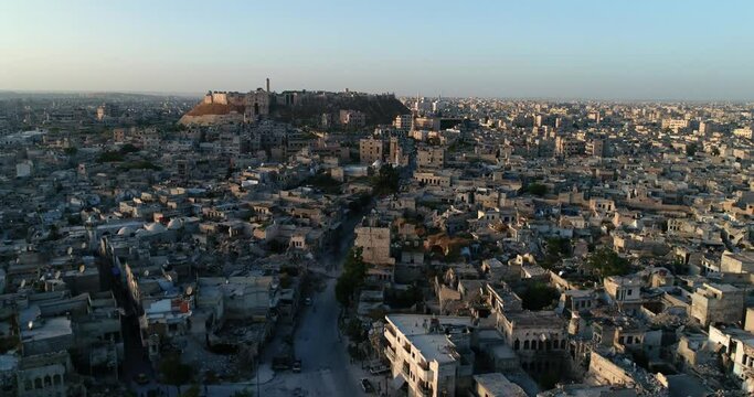 The citadel of Aleppo under the sunset. We can see the syrian city all over the horizon - aerial view with a drone 4K