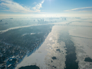 The frozen Dnieper river in Kiev in sunny weather. Aerial drone view. Winter sunny morning.