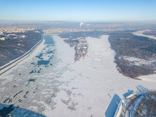 The frozen Dnieper river in Kiev in sunny weather. Aerial drone view. Winter sunny morning.