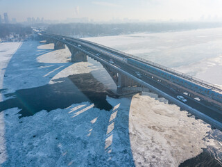 Aerial drone view. The Kiev metro train travels across the bridge through the Dnieper river. Winter...