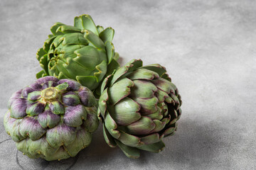 Fototapeta premium Fresh ripe artichokes flowers vegetable on gray background. Healthy vegetarian food