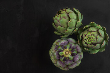 Fototapeta premium Fresh ripe artichokes flowers vegetable on black background. Healthy vegetarian food. top view with copy space