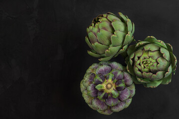 Fresh ripe artichokes flowers vegetable on black background. Healthy vegetarian food. top view with copy space