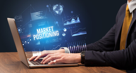 Businessman working on laptop with MARKET POSITIONING inscription, new business concept