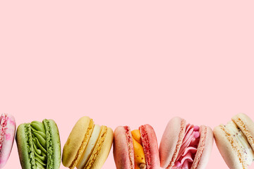 Traditional french cookies macarons of different colors and taste isolated on pink background with copy space. Sweet cookies macaron. Mockup for the card on the celebrated birthday.