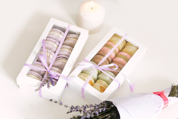 Macaroons colorful cookies in box on white  table.Above view on a cookie in gift box next to the candle and lavender,selective focus