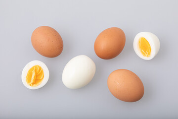 Hard boiled egg with shell and peeled boiled egg on white background