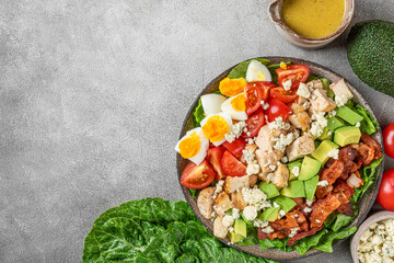 Cobb salad. Classic American salad with tomato, bacon, grilled chicken, eggs, avocado, blue cheese on gray background