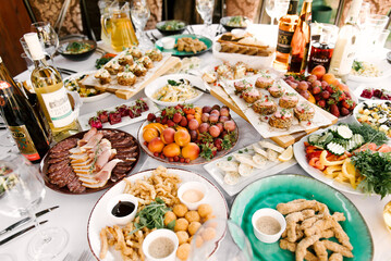 The feast of the round table full of delicious food and snacks, a beautiful setting, catering, holiday in the fresh air