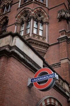 St Prancras London Underground Station And Red Underground Sign On The Building Against Cloudy Sky