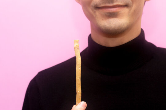 Guy hold miswak. Bokeh effect. Teeth cleaning. Sunnah. Sivak. Pink background.