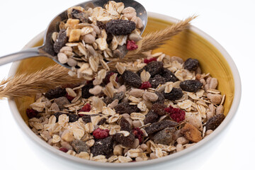 Breakfast oatmeal with nuts and dried fruits in yellow bowl on white