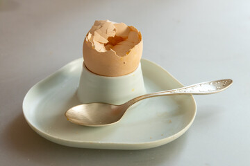 Soft-boiled egg. Breakfast scraps, egg shells, unwashed dishes, dirty egg stand.