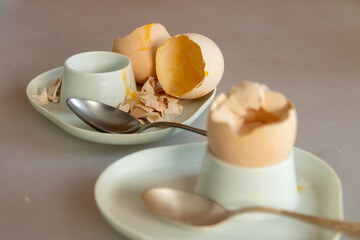 Soft-boiled egg. Breakfast scraps, egg shells, unwashed dishes, dirty egg stand.