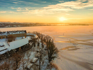 Blick &uuml;ber den zugefrorenen S&uuml;&szlig;en See mit dem Schloss Seeburg im Sonnenuntergang